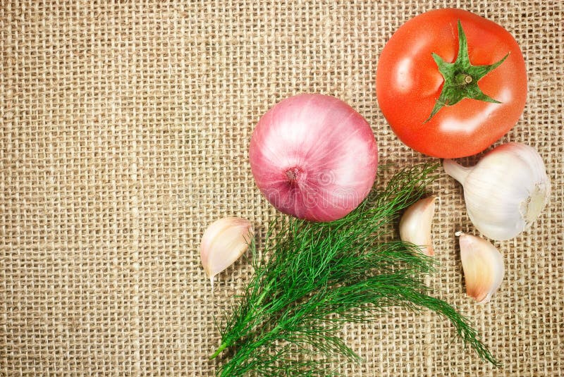 Tomato onion and garlic vegetables on sacking background texture