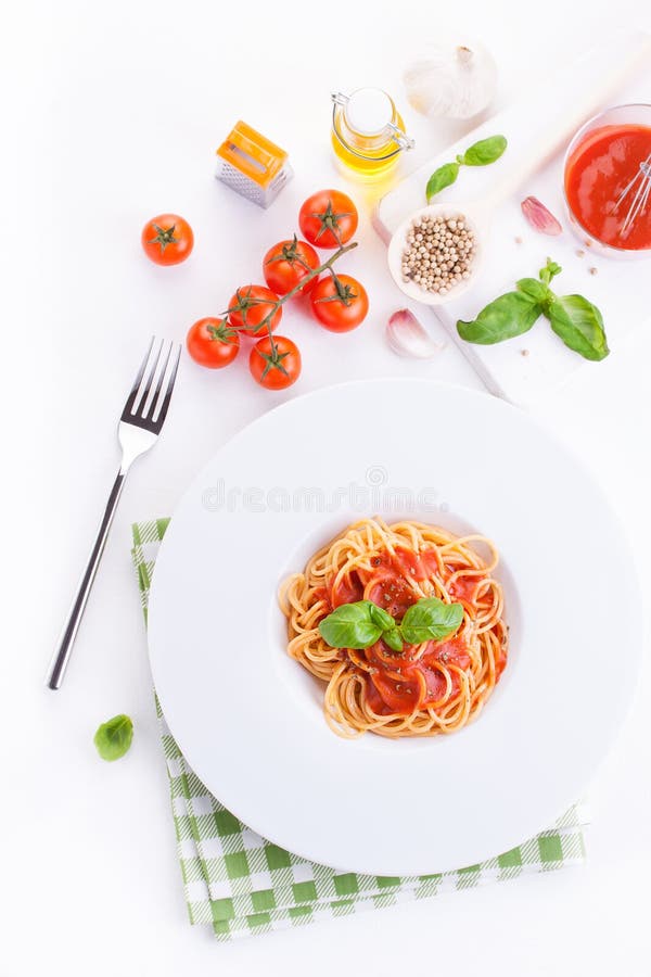 Tomato pasta spaghetti with fresh tomatoes, basil, italian herbs and olive oil in a white bowl on a white wooden background