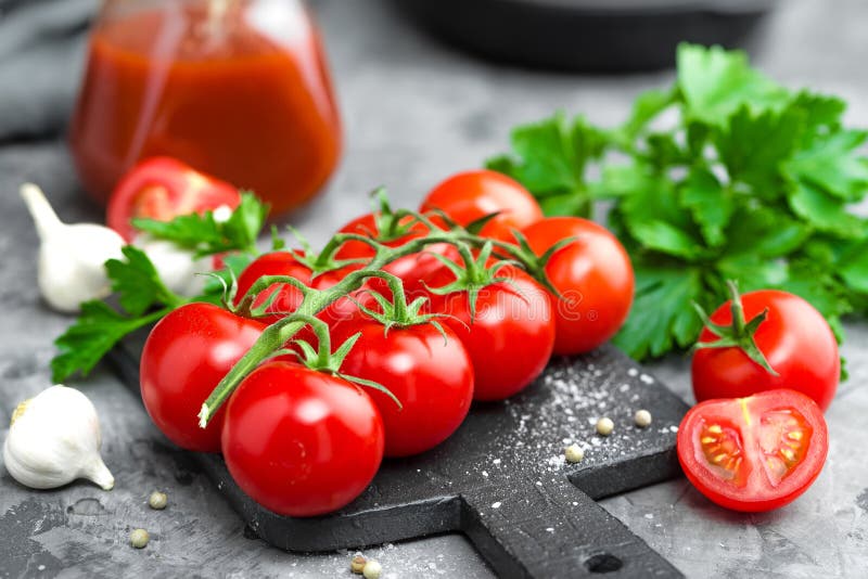 Tomato Paste, Puree in Glass Jar and Fresh Tomatos on Dark Background