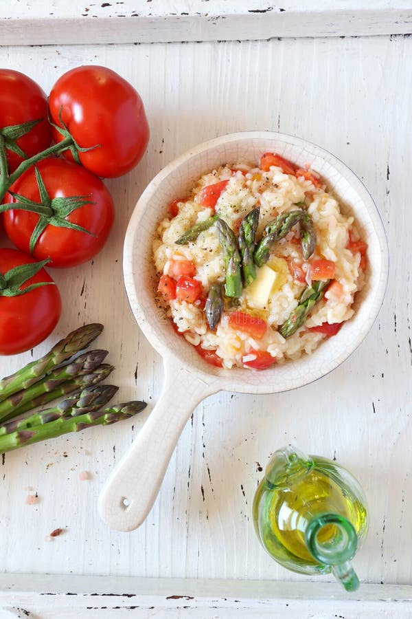 Tomato risotto with green asparagus, bunch of tomatoes and olive oil