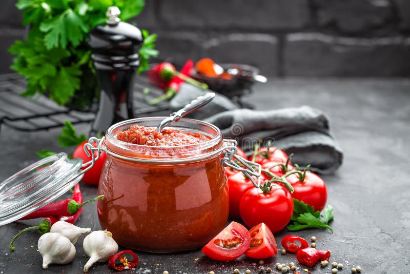 Tomato sauce in glass jar and fresh tomatoes