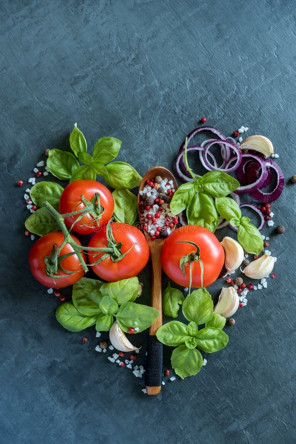 Tomatoes Basil Garlic and spices on a stone table in the form of heart healthy food Concept.