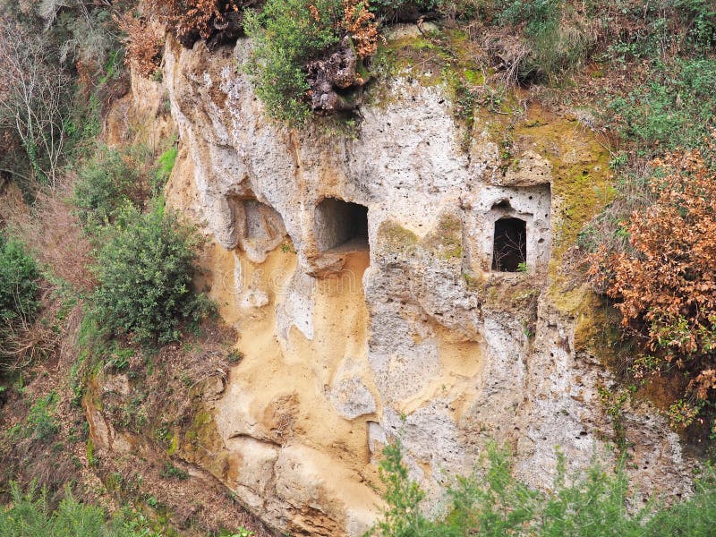 Tomb entrances in the cliff wall of a Via Cava, an ancient Etruscan road carved through tufo cliffs in Tuscany