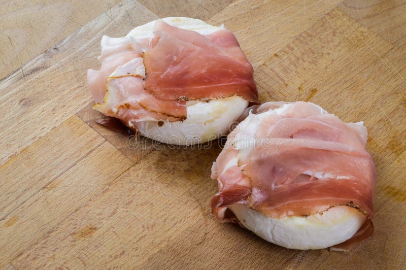 Tomino delicious cow`s milk cheese from Piedmont, Italy rolled with speck italian smoked ham ready to be heated. Before degustation. - close up stock photography Tomino delicious cow`s milk cheese from Piedmont, Italy rolled with speck italian smoked ham ready to be heated. Before degustation. - close up stock photography