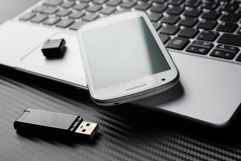 Tomma Smartphone med den gröna reflexionen som ligger på affärsanteckningsboktangentbordet bredvid en USB lagring, allt ovanför e royaltyfri fotografi Tomma Smartphone med den gröna reflexionen som ligger på affärsanteckningsboktangentbordet bredvid en USB lagring, allt ovanför e royaltyfri fotografi