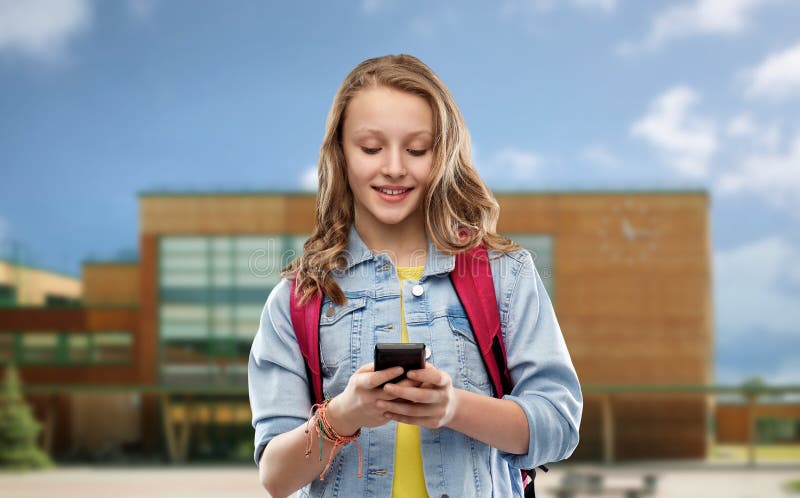 Ton?rig studentflicka med skolap?sen och smartphonen arkivfoton Ton?rig studentflicka med skolap?sen och smartphonen arkivfoton