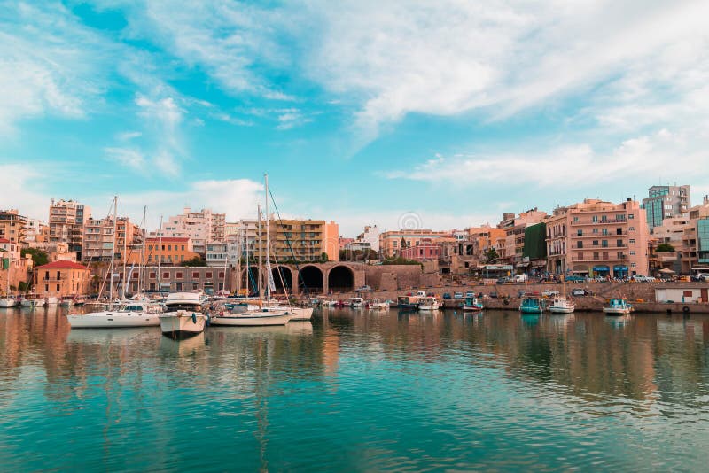 Tonen skiftade fotoet av fartyg för himmel för havet för panoramautsikten för gammal port för den heraklion staden som svävar och royaltyfri foto Tonen skiftade fotoet av fartyg för himmel för havet för panoramautsikten för gammal port för den heraklion staden som svävar och royaltyfri foto