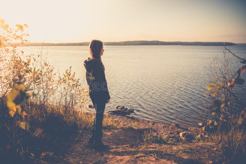 Thoughtful teen girl in casual cloth alone looking to water at sunset. Thoughtful teen girl in casual cloth alone looking to water at sunset