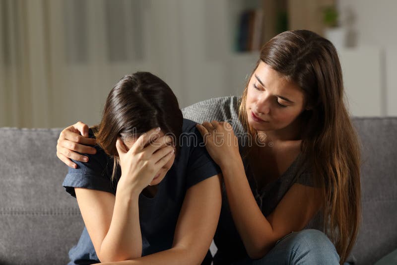 Teen comforting hes sad friend in the night sitting on a couch in the living room at home. Teen comforting hes sad friend in the night sitting on a couch in the living room at home