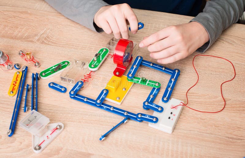 Teen boy hands with parts of electronic constructor. Student doing school electronic project in his room at home. Teen boy hands with parts of electronic constructor. Student doing school electronic project in his room at home.