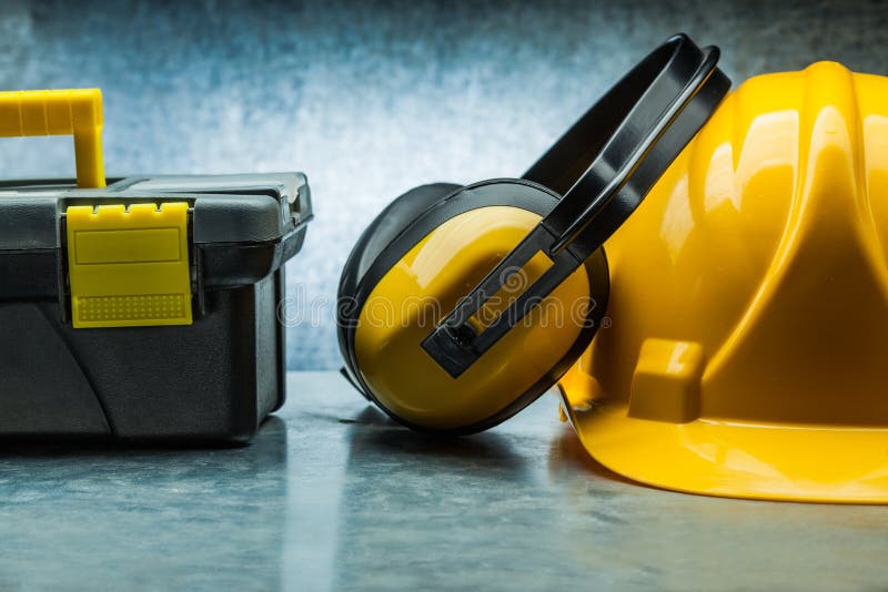 Tool box earphones and yellow construction helmet on metalic background royalty free stock image