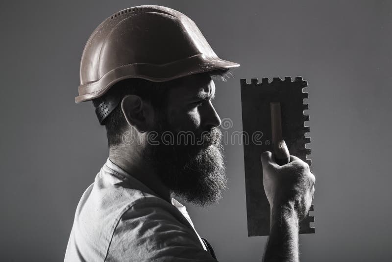 Tool, trowel, handyman, man builder. Mason tools, builder. Bearded man worker, beard, building helmet, hard hat stock photo Tool, trowel, handyman, man builder. Mason tools, builder. Bearded man worker, beard, building helmet, hard hat stock photo