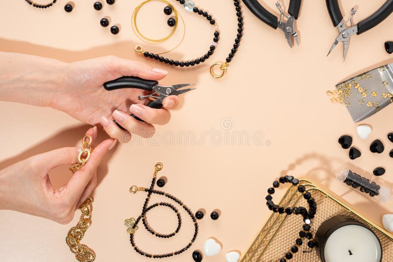Tools and accessories for DIY jewelry in the workplace. Female hand with wire cutters.Flat lay on beige background.Creative flat