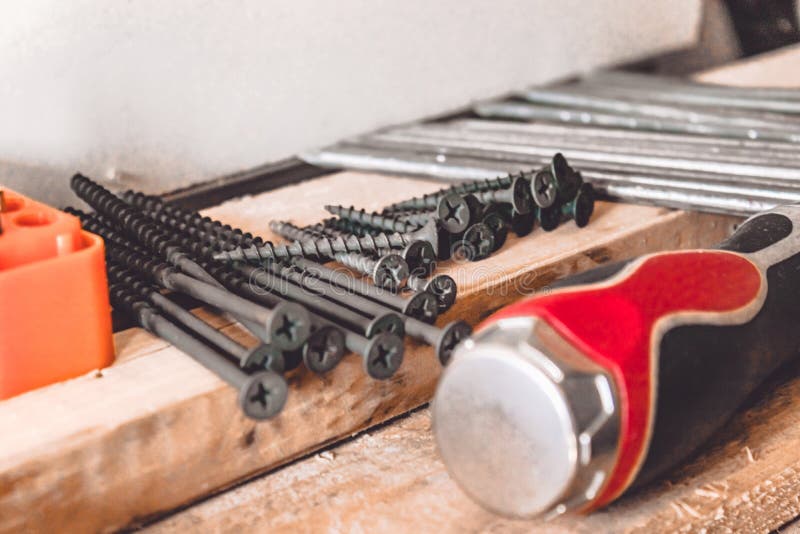 Tools for the Job. Screws, Nails and a Screwdriver are on the Table. Carpentry Tools Stock Photo