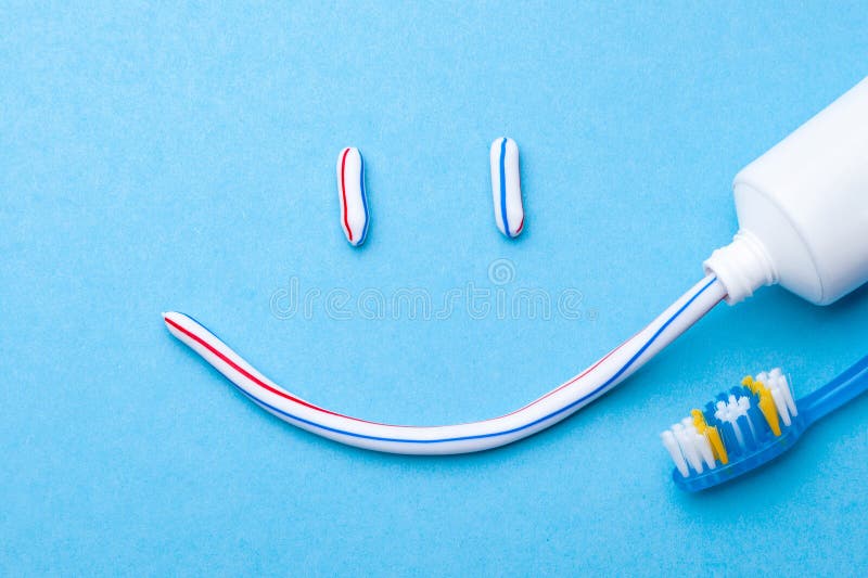 Tooth-paste in the form of face with a smile. Tube of toothpaste and toothbrush on blue background. Refreshing and whitening toothpaste. Tooth-paste in the form of face with a smile. Tube of toothpaste and toothbrush on blue background. Refreshing and whitening toothpaste.