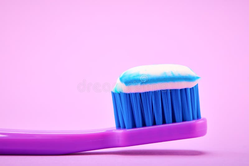 Toothpaste on a purple toothbrush on lilac background royalty free stock photography
