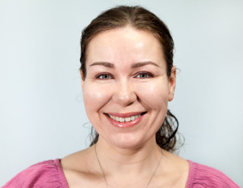 Toothy lächelnde erliche erwachsene Frau, Portrait auf grauem Hintergrund, Emotionen Serie stockfotos