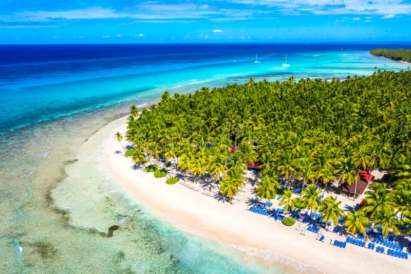 Top aerial drone view of beautiful beach with turquoise sea water, boats and palm trees. Saona island, Dominican republic.