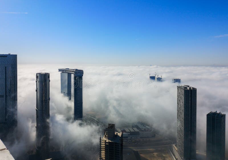 Top aerial view shot of skyscrapers in the city with fog clouds passing by - Abu Dhabi Al Reem island Sun and Sky towers royalty free stock photo