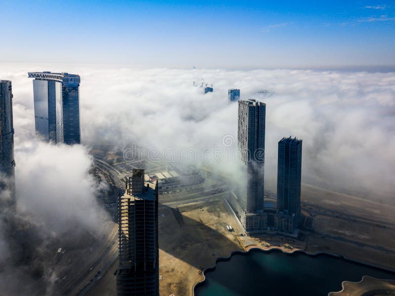 Top aerial view shot of skyscrapers in the city with fog clouds passing by - Abu Dhabi Al Reem island towers stock photography