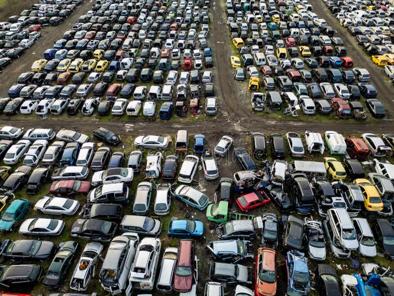 Top down aerial view of an abandoned car graveyard filled with old, damaged and unused vehicles arranged in dense rows. Concept of stock image