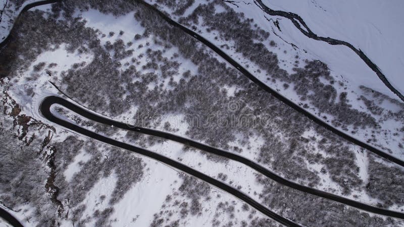 Top down, ascending aerial footage of a winding road passing through a snowy mountain in Armenia stock video footage
