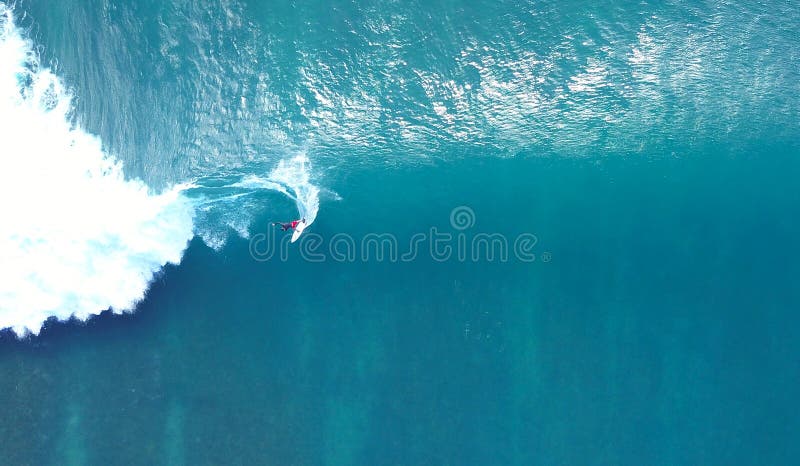 TOP DOWN: Unrecognizable pro surfer riding a stunning blue ocean wave in the sun stock photo