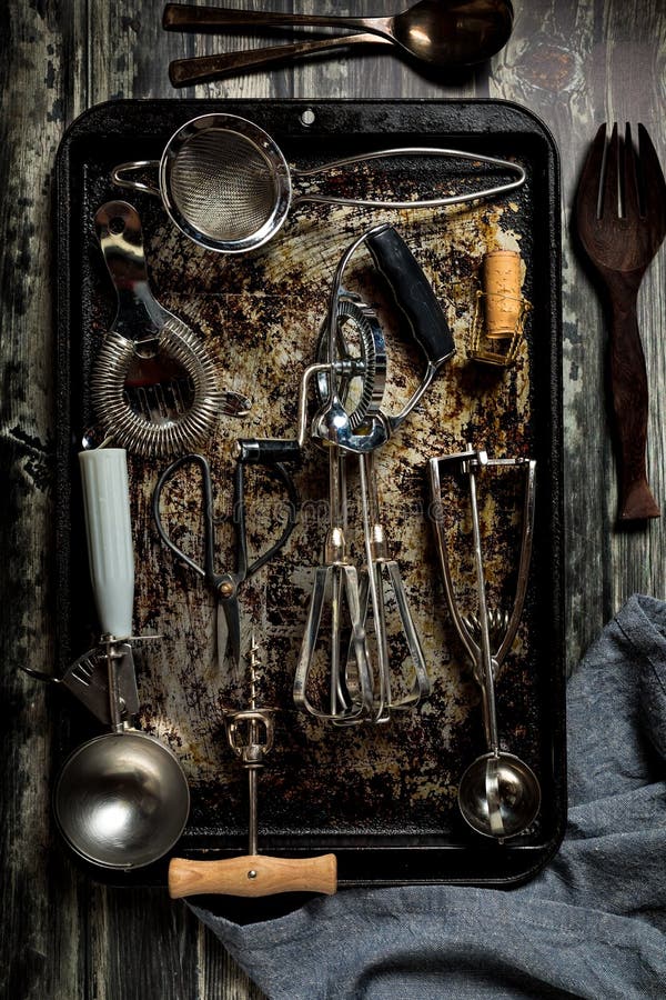 A top down view of an abstract arrangement of antique utensils on a baking sheet against a dark background. royalty free stock photos