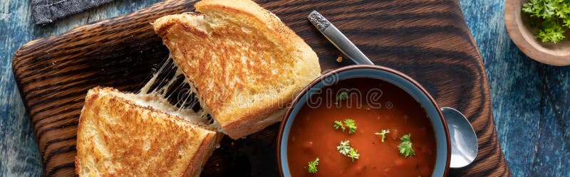 Top down view of a grilled cheese sandwich served with a bowl of tomato soup, ready for eating.