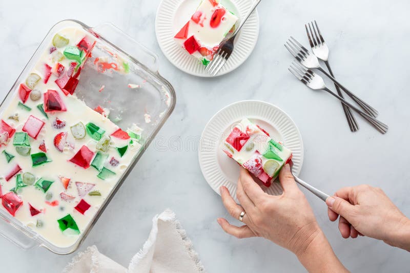 Top down view of hands serving a square of homemade gelatin dessert. royalty free stock photos