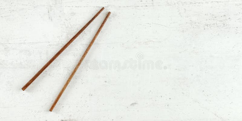 Top down view - pair of dark wood chopsticks on white board. Can be used as banner for asian / chinese food, space for text on royalty free stock photos Top down view - pair of dark wood chopsticks on white board. Can be used as banner for asian / chinese food, space for text on royalty free stock photos