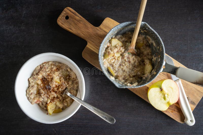 Top down view of preparation of oatmeal porridge with apple, cinnamon and raisins, bowl of oatmeal with spoon stock images