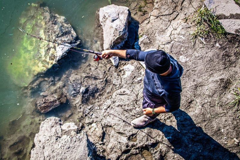 Top down view of unrecognizable man with cap fishing for salmon in Ship Creek near downtown stock photos
