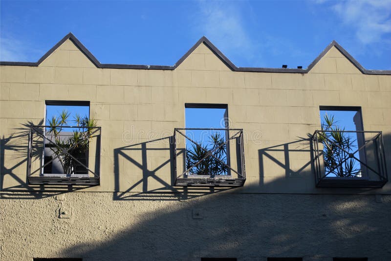 Top Roof Floor of a Building with Plants on Three Balcony Windows Stock