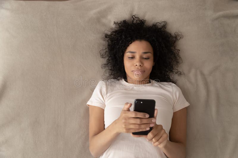 Top view of black girl relaxing in bed using cellphone stock images Top view of black girl relaxing in bed using cellphone stock images