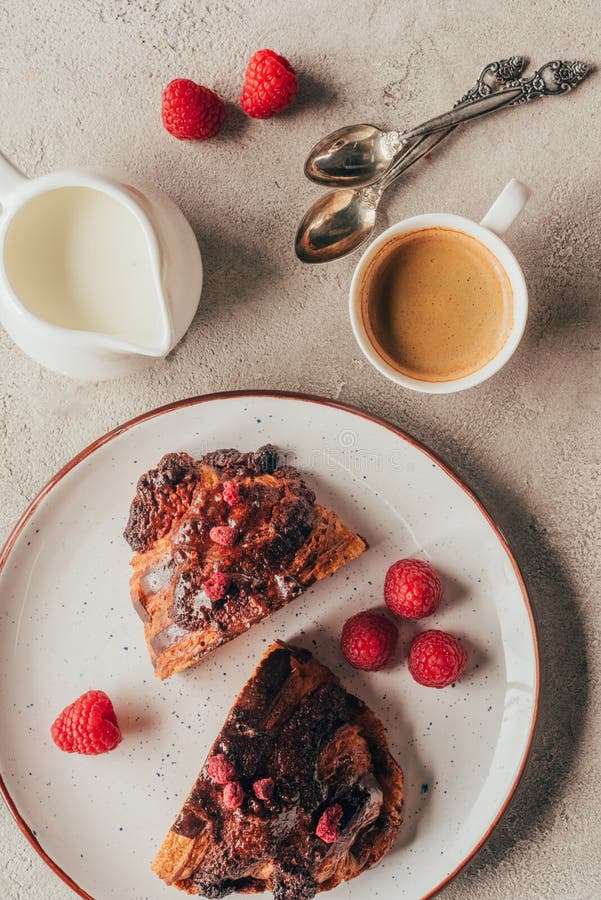 top view of arrangement of cup of coffee and sweet pastry with raspberries on plate