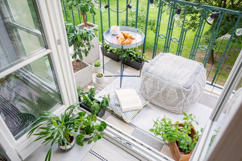 Balcony with plants, pouf a table with breakfast. Top view of a balcony with plants, pouf a table with breakfast stock photography