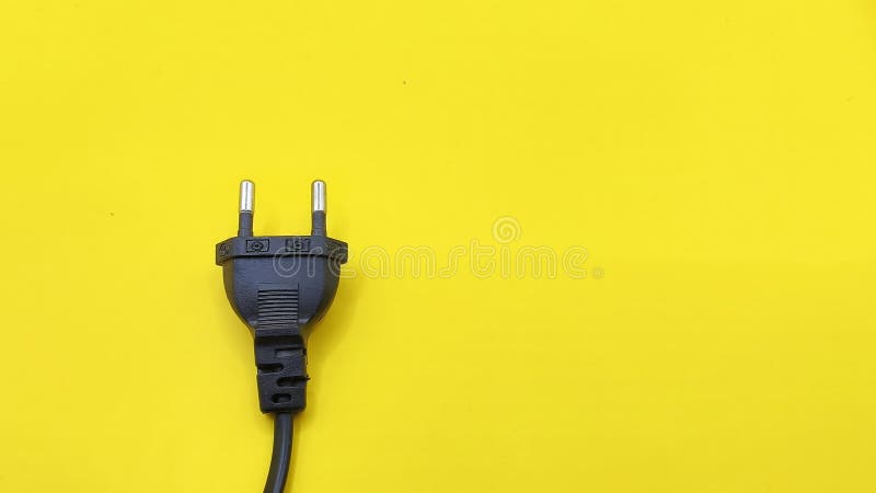 Top view of black electrical plug isolated on yellow background. rules of thirds composition stock photo