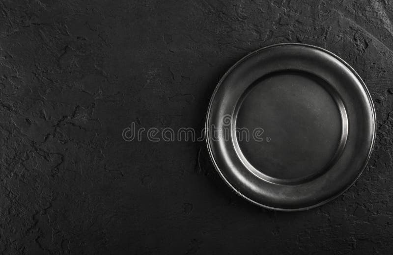Top view of black empty plate on black stone background stock images
