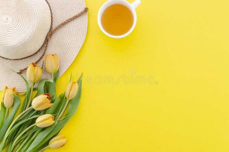 Top view bouquet tulips on the yellow background, tea and hat, flat lay summer breakfast concept