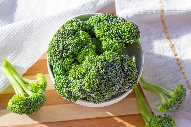 Top view of bright green organic raw broccoli branches in the white bowl on the table in the kitchen close up. royalty free stock image Top view of bright green organic raw broccoli branches in the white bowl on the table in the kitchen close up. royalty free stock image