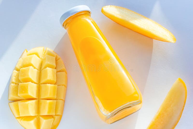 Top view of bright yellow mango juice in a glass bottle with sliced fresh mangos on white background royalty free stock photos Top view of bright yellow mango juice in a glass bottle with sliced fresh mangos on white background royalty free stock photos