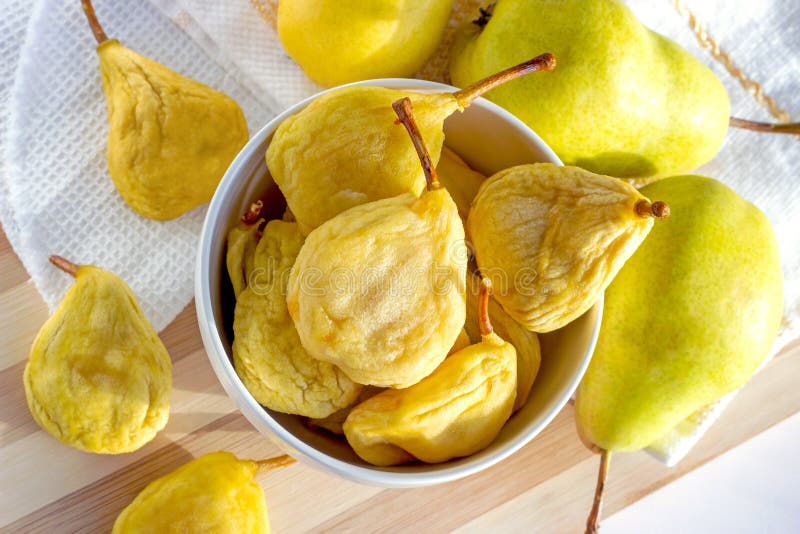 Top view of bright yellow whole dried pears in the white bowl and fresh fruit on the wooden background. stock images Top view of bright yellow whole dried pears in the white bowl and fresh fruit on the wooden background. stock images