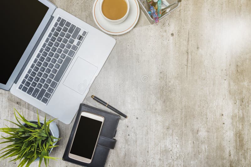 Top view of business desk with laptop, mobile phone, coffee, potted plant, notebook and business accessories