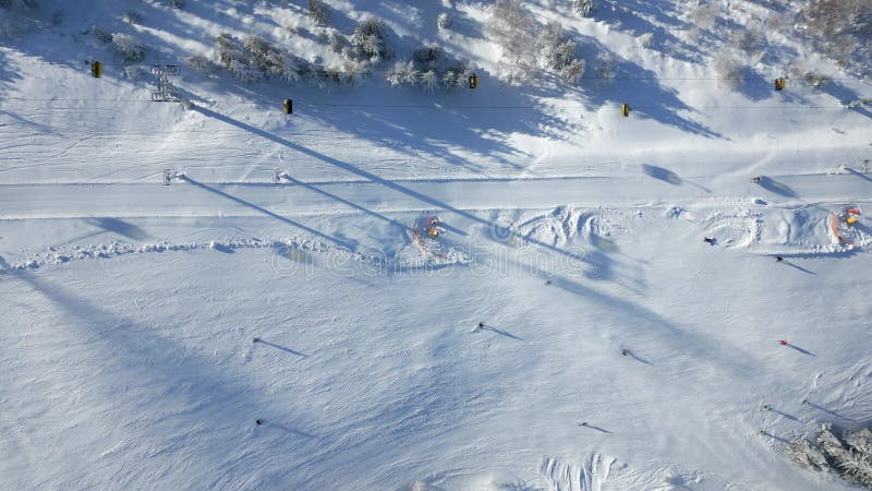 Top view of a chairlift and people skiing on a snowy mountain slope. stock video