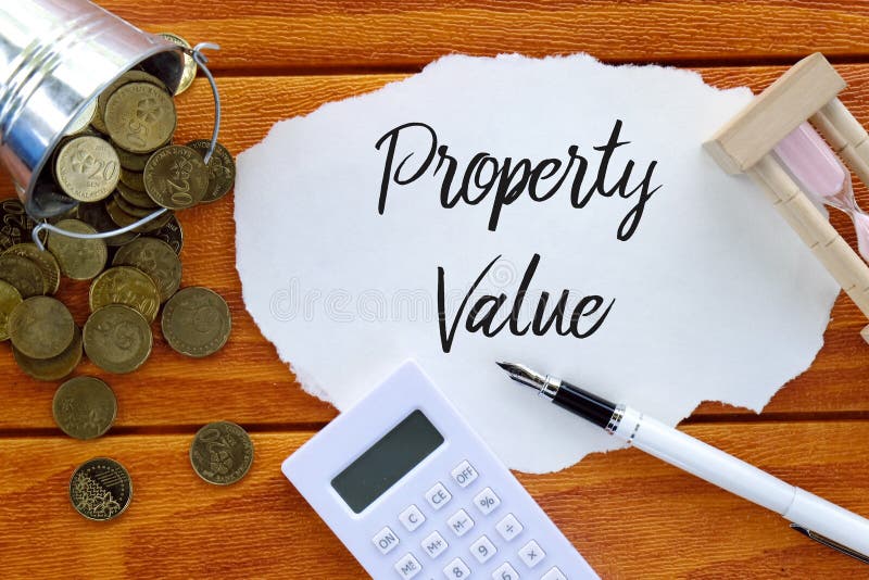 Top view of coins,calculator,sand clock,pen and piece of paper written with Property Value on wooden background. Business and finance concept