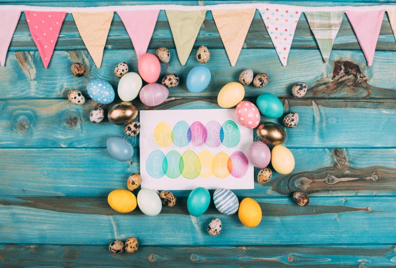 top view of colorful happy easter greeting card with colorful eggs around on blue