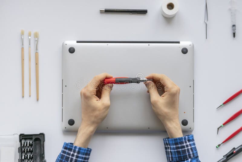 A top view of the computer master in the service fixing the laptop computer on white table