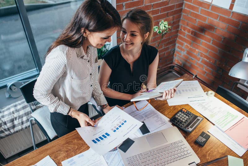 Top view of concentrated young women sitting at the table and working together stock photo