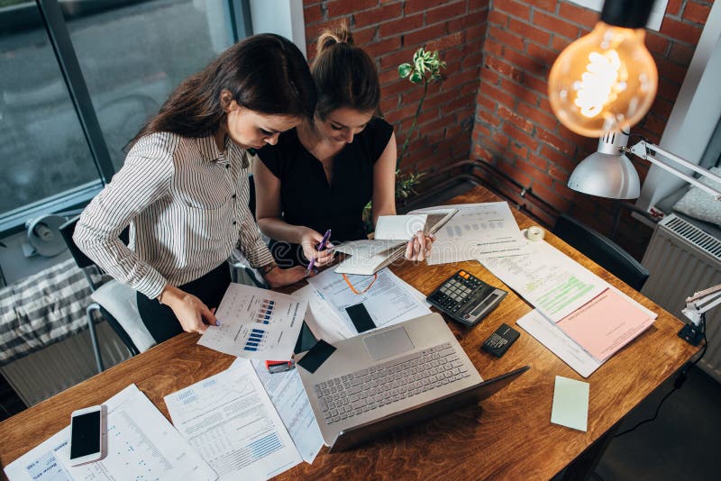 Top view of concentrated young women sitting at the table and working together royalty free stock photos